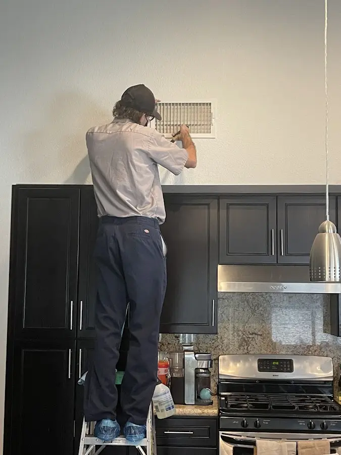 Technician inspecting an air vent during HVAC service in Newton